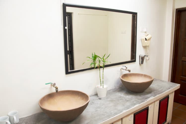 手洗い場の写真。鏡と水道と飾られた花