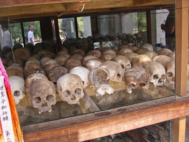 キリングフィールドの写真。人間の頭部の骸骨がたくさん並んでいる。左手前には世界平和祈願という文字が見える。写真