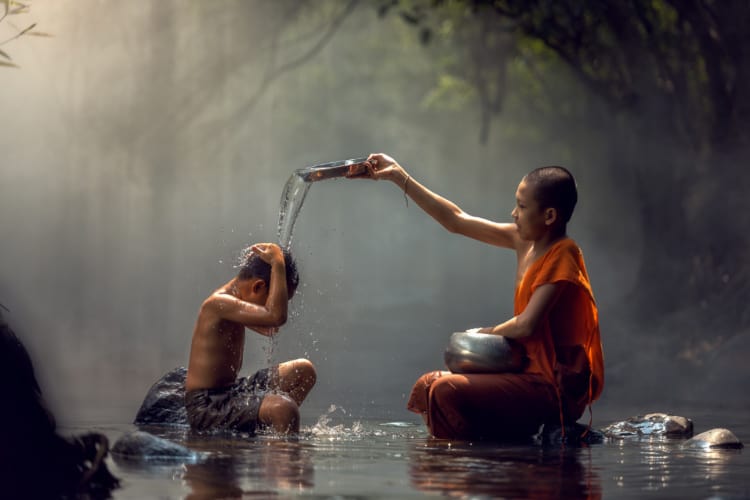 少年僧侶がより幼い少年に水をかけている写真