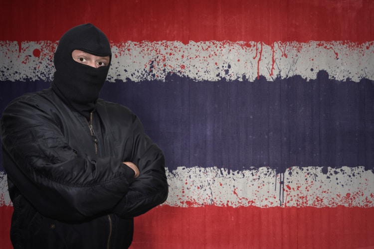 タイ国旗の前でマスクの男が立っている