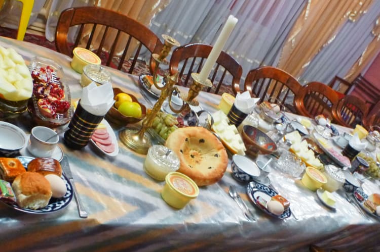テーブルの上にパンや果物などたくさんの食べ物が乗っている写真