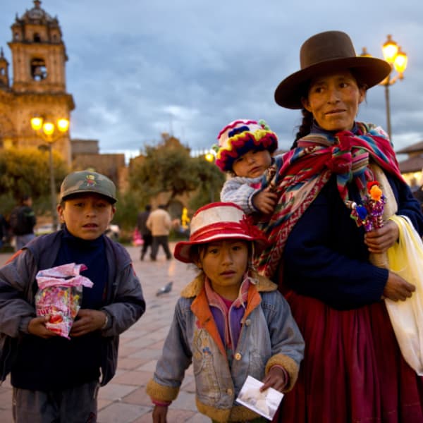 ペルー人の家族。年配の女性とその女性に背負われた小さい子供、そばにたつ二人の子ども達の写真