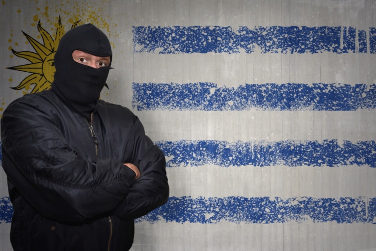 ウルグアイ国旗の前にマスクの男がたっている