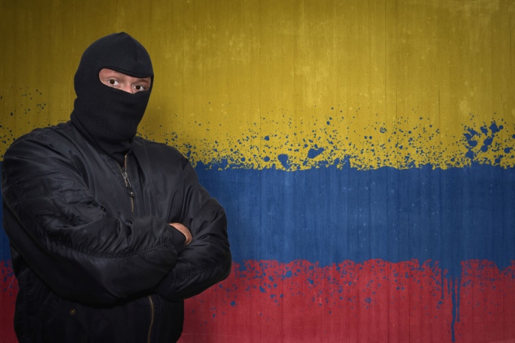 コロンビア国旗の前にマスクの男が立っている
