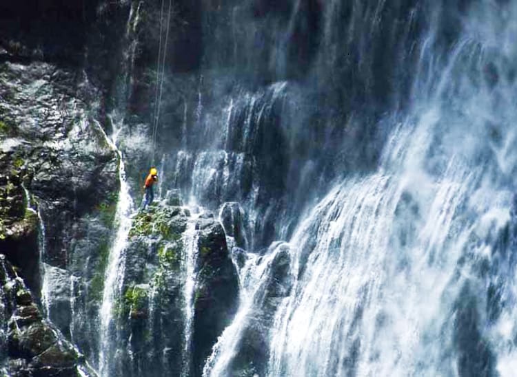 滝の中を懸垂下降している人の写真