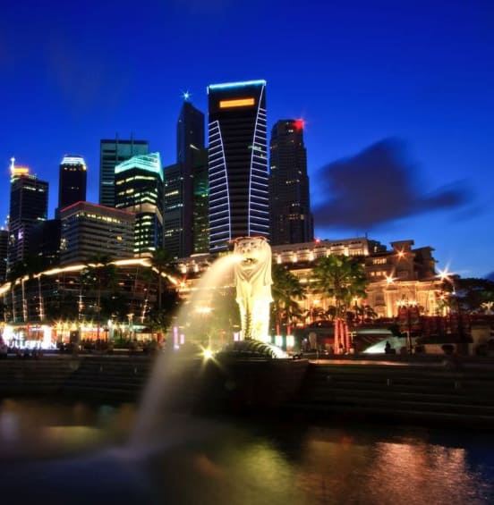 夜景をバックにシンガポールのマーライオンが水を吐いている