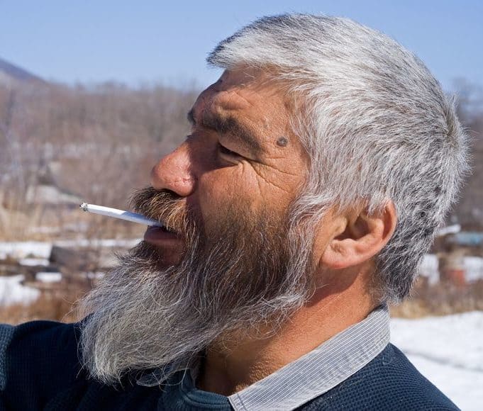 タバコを吸う白髪の年配男性