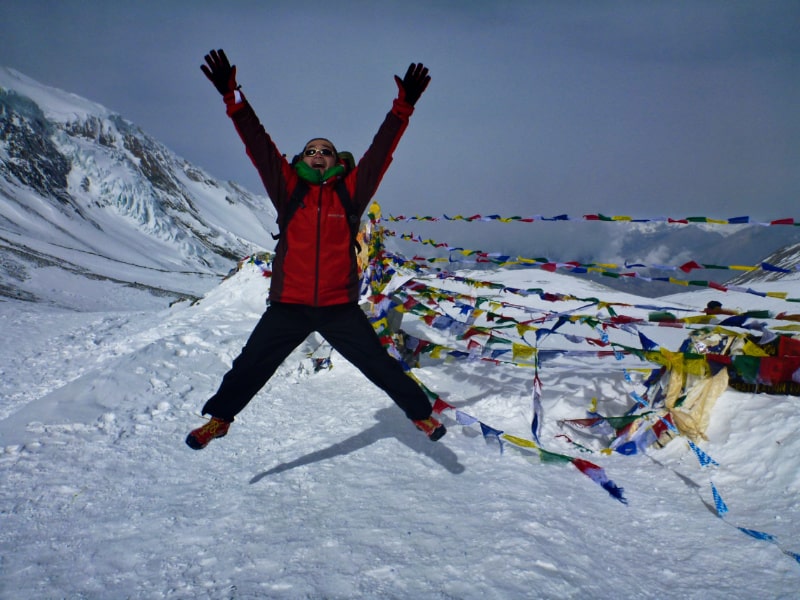 雪山の上で男性が手を広げてジャンプしている写真