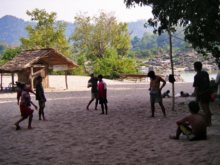 砂浜にネットを張ってビーチバレーをしているたくさんの子ども達