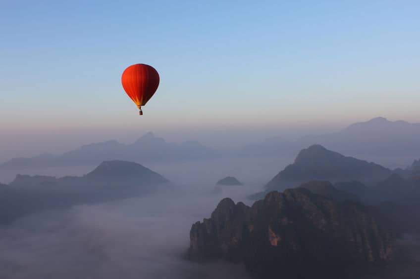 霧が掛かった山の上に気球が浮いている写真