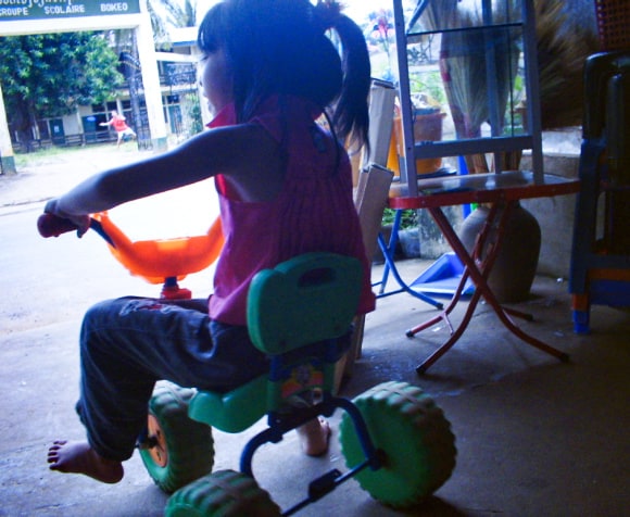 ラオスの小さい女の子がおもちゃの三輪車に乗っている写真